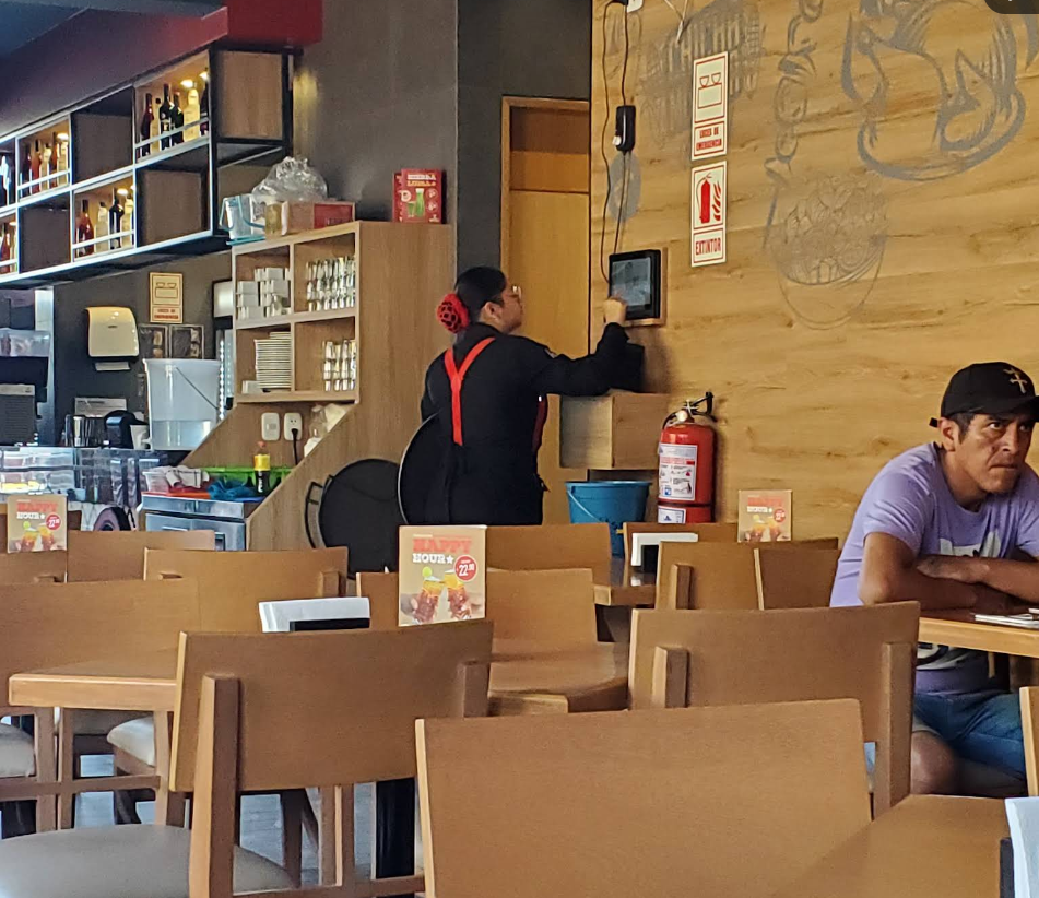 Salón interior con mesas de madera y atención en Leña & Carbón